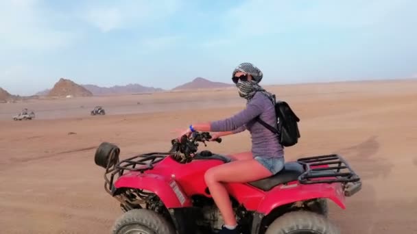 Mujer está montando una bicicleta cuádruple en el desierto de Egipto. Vista dinámica en movimiento . — Vídeos de Stock