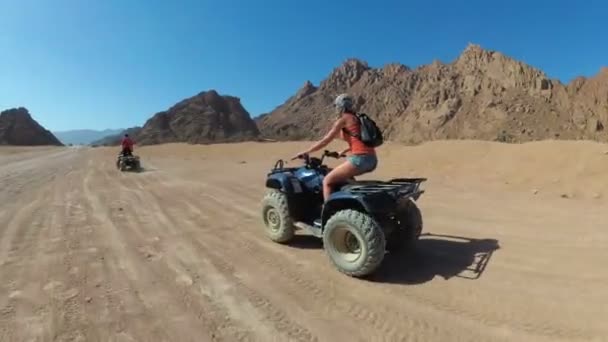 Sexy Girl está montando una bicicleta cuádruple en el desierto de Egipto. Vista dinámica en movimiento . — Vídeos de Stock