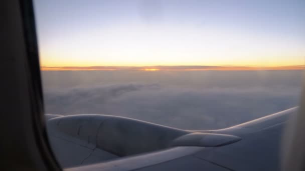 La vista desde la ventana de un panel de pasajeros volando en las nubes al atardecer por la noche . — Vídeo de stock