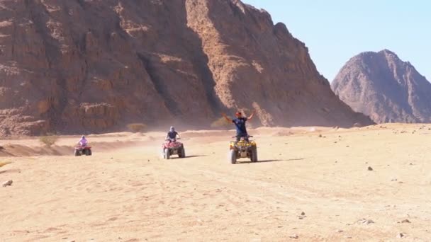 Група на чотирьохядерних велосипедах їде через пустелю в Єгипті на тлі гір. Водіння квадроциклів. — стокове відео