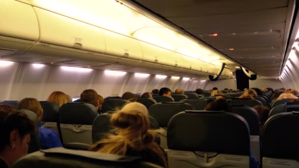 Passagerare inne i kabinen på passagerarflygplan sitter på stolarna under flygningen på natten — Stockvideo