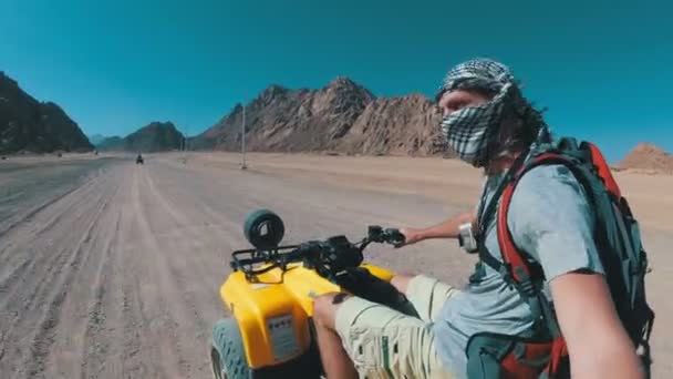 男はエジプトの砂漠でクワッドバイクに乗って、アクションカメラで自分自身を撮影しています — ストック動画