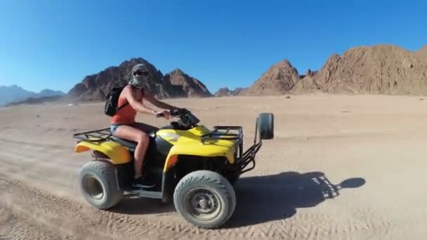 Sexy Girl está montando una bicicleta cuádruple en el desierto de Egipto. Vista dinámica en movimiento . — Vídeos de Stock