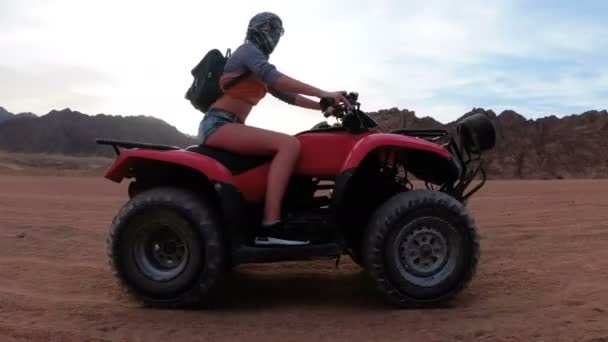 女性はエジプトの砂漠でクワッドバイクに乗っています。モーションでのダイナミック ビュー. — ストック動画