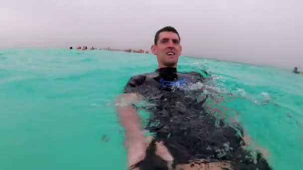 Młody mężczyzna w kombinezon nurkowy pływa w otwartym morzu czerwonym z turystami, Egipt. — Wideo stockowe