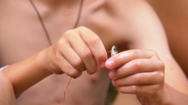 Childrens hands string fresh caught fish on a wire — Stock Video