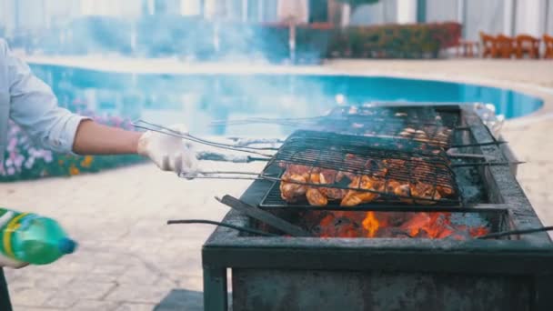 O churrasco de frango é cozido em uma grelha grande por um cozinheiro no hotel junto à piscina com água azul. Egipto — Vídeo de Stock