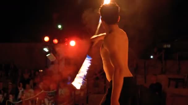 Feuershow auf der Bühne. junger Mann tanzt mit feurigen Fans in einer Nachtshow. Zeitlupe — Stockvideo