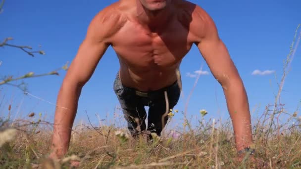 裸の胴体を持つ若い運動選手が自然にプッシュアップを行う — ストック動画