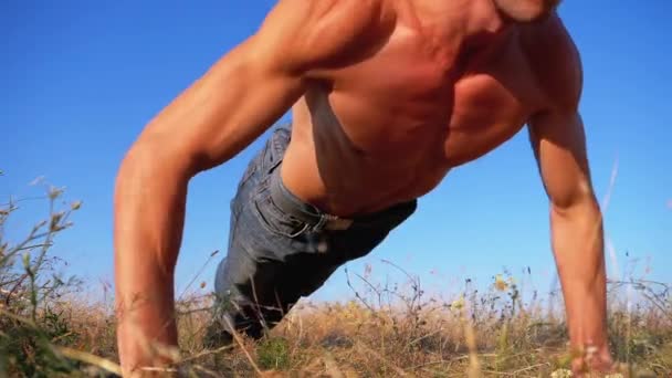 Entraînement. Homme fort faisant des pompes avec des applaudissements à l'extérieur sur la nature. Mouvement lent — Video