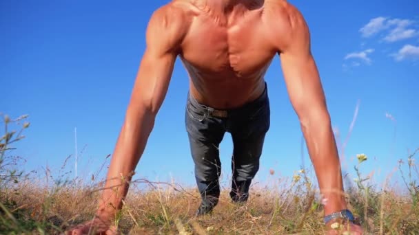 벌거벗은 몸통을 가진 젊은 운동남자가 자연에 박수를 치며 팔밀어 올리는 것을 한다. 슬로우 모션 — 비디오