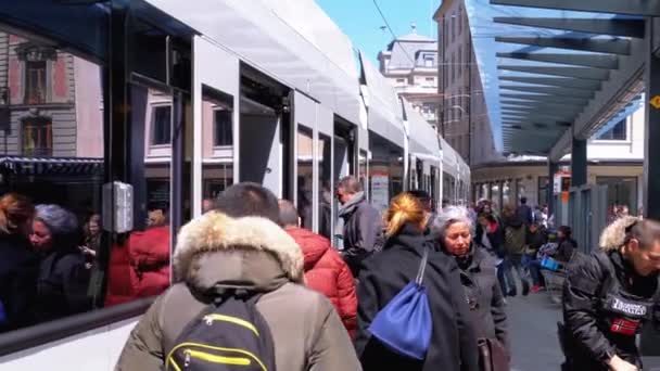 Folkmassan går in i en spårvagn vid en hållplats för kollektivtrafiken i Genève, Schweiz. — Stockvideo