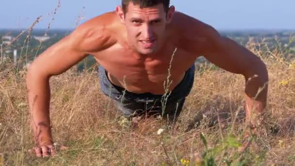 Young Athletic Man with a Bare Torso Performs Pushups on the Nature — Stock Video