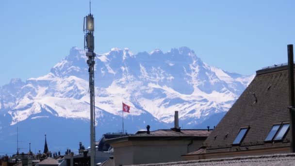 Liggande vy på tak av schweiziska hus och Schweiz flagga på snöiga Alperna bakgrund — Stockvideo