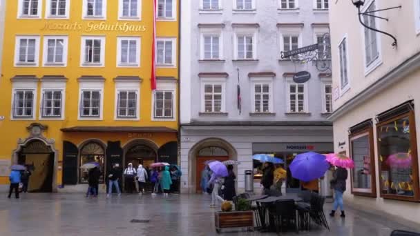 Maison Mozarts. Les gens avec des parapluies marchent dans les rues du vieux Salzbourg pendant la pluie. Autriche — Video