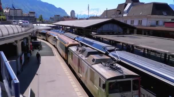 Schweiziska järnvägsstationen. Moderna tåg anländer till plattformen i tågstationen. — Stockvideo