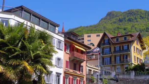 Красивые разноцветные швейцарские дома на фоне гор на улице маленького городка — стоковое видео