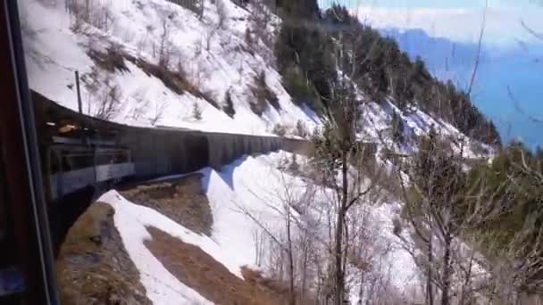 Il treno turistico Cogwheel a scartamento ridotto viaggia tra le montagne innevate. Svizzera, Alpi — Video Stock