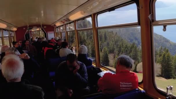 Vista desde la cabina del tren de pasajeros de montaña en movimiento con los turistas en las ventanas. Suiza — Vídeos de Stock