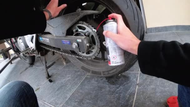 Motociclista lubrifica uma corrente de motocicleta usando uma lata de pulverização. Visão em primeira pessoa — Vídeo de Stock