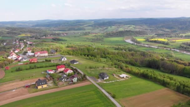 Drohnenaufnahmen von grünen Feldern, Hügeln und Bäumen in einem Dorf mit kleinen Häusern. Polen. — Stockvideo