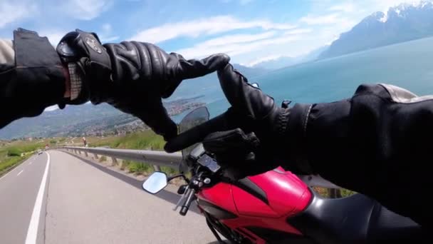 Путешествие на мотоцикле. Байкер в перчатках показал фотографию знака на Женевском озере и в швейцарских Альпах — стоковое видео