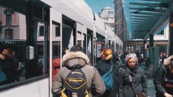 İsviçre'nin Cenevre kentinde ki toplu taşıma durağında tramvaya insan kalabalığı giriyor. — Stok video