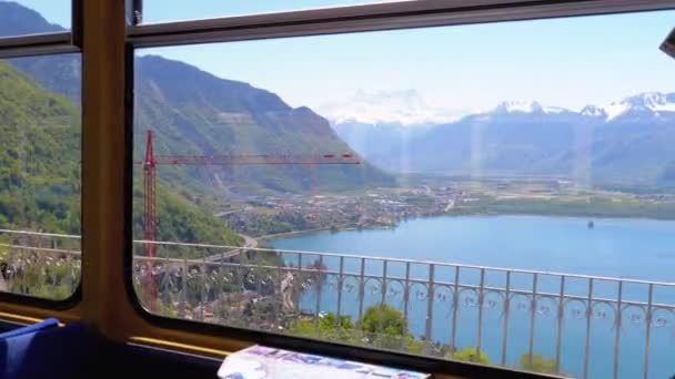 Blick aus dem Fenster der Bergbahn auf das schweizerische Dorf, die Stadt Montreux, den Genfersee und die Alpen. — Stockvideo