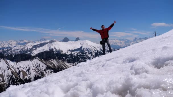 Junger Mann auf dem Gipfel der alpinen Berge springt und jubelt über das Tor. Schweiz — Stockvideo