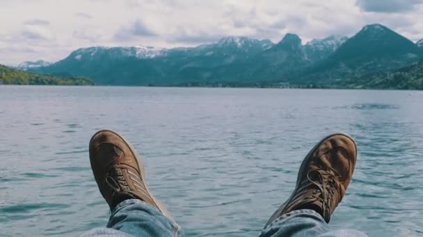 Az emberi lábak a háttérben egy hegyi tó és hóval borított hegység. — Stock videók