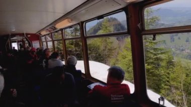 Pencerelerde turistler ile hareket eden yolcu dağ treninin kabin görünümü. İsviçre