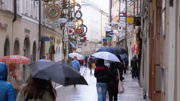 Emberek napernyők séta az utcákon a régi salzburgi alatt Rain. Ausztria — Stock videók