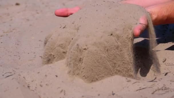 Mężczyzna ręce spada piasek na plaży w zwolnionym tempie. Brudny piasek w rękach mężczyzn — Wideo stockowe