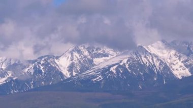 Karla kaplı Yüksek Tatras'ın panoramik manzarası. Bulutlarda dağ zirveleri