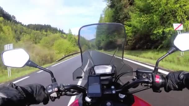 Motocyklista jazda na pięknej pustej drodze w pobliżu zielonych drzew i wzgórz — Wideo stockowe