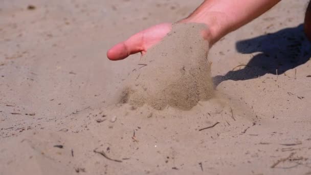 Sand fällt in Zeitlupe aus der Hand eines Mannes am Strand. Schmutziger Sand in der Hand der Männer — Stockvideo