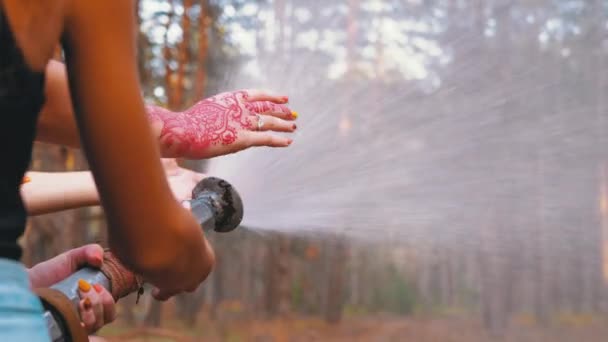 Детки держат в руках пожарный шланг, из которого течет вода в сосновом лесу — стоковое видео
