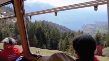 Pencerelerde turistler ile hareket eden yolcu dağ treninin kabin görünümü. İsviçre