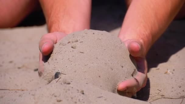 Άμμος που πέφτουν από αρσενικά χέρια στην παραλία σε αργή κίνηση. Βρώμικη άμμος στα χέρια των αντρών — Αρχείο Βίντεο