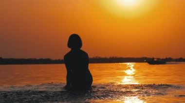 Gün batımında Kadın Siluet Ilerler Eller yükseltir ve Su Sıçramaları Oluşturma. Yavaş çekim