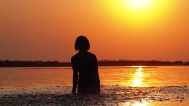 Gün batımında Kadın Siluet Ilerler Eller yükseltir ve Su Sıçramaları Oluşturma. Yavaş çekim