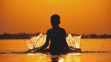 Gün batımında Boy Siluet Eller Yükseltir ve Su Sıçramaları Oluşturma. Yavaş çekim