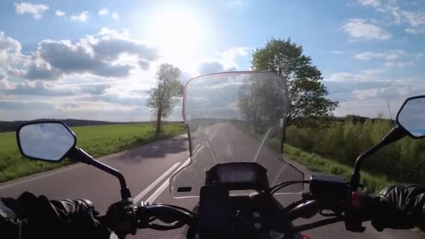 Motocyklista jazda na pięknej pustej drodze w pobliżu zielonych pól i wzgórz. Widok pierwszoosobowy — Wideo stockowe