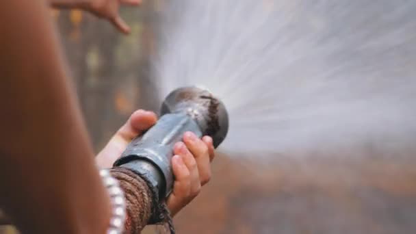 Childrens női kéz tartsuk tűz tömlő ahonnan víz fut fenyőerdőben — Stock videók