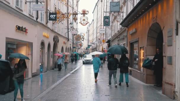 Люди з парасольками ходять по вулицях старого Зальцбурга під час дощу. Австрія — стокове відео