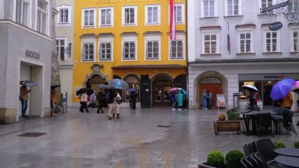 Mozarts hus. Människor med paraplyer går på gatorna i gamla Salzburg under regnet. Österrike — Stockvideo