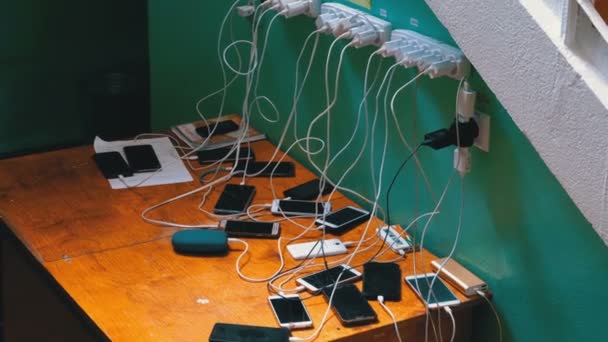 Muchos teléfonos inteligentes y teléfonos móviles de carga sobre la mesa — Vídeos de Stock