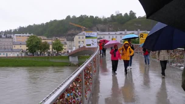 Mensen met parasols lopen op de Liefdesbrug in Salzburg tijdens de regen, Oostenrijk. — Stockvideo