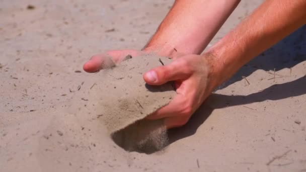 Písek padá z mužské ruky na pláž v pomalém pohybu. Špinavý písek v rukou mužů — Stock video