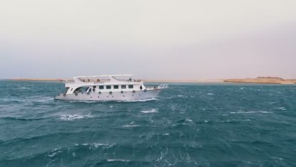 観光客と遊覧船は、岩の背景に嵐の海で航海します。エジプト — ストック動画
